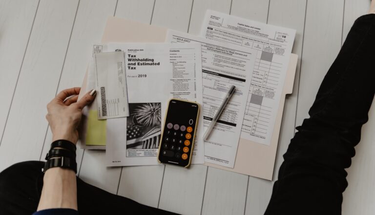 Person Holding Paper Near Pen And Calculator XoU52jUVUXA