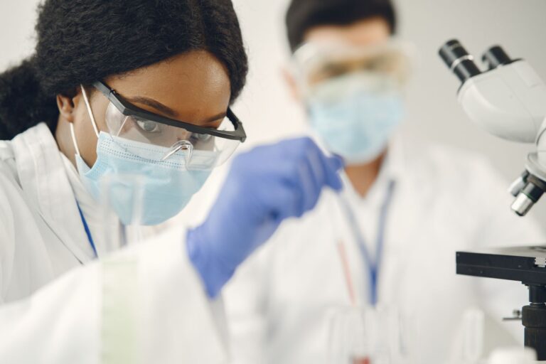 Scientists in protective gear examining samples in a modern laboratory setting.