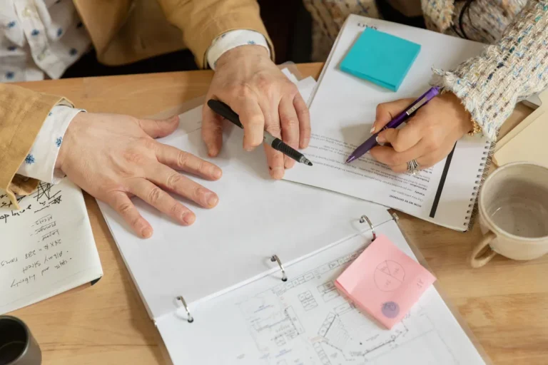 Close-up of two coworkers collaborating over documents and planning in an office setting.