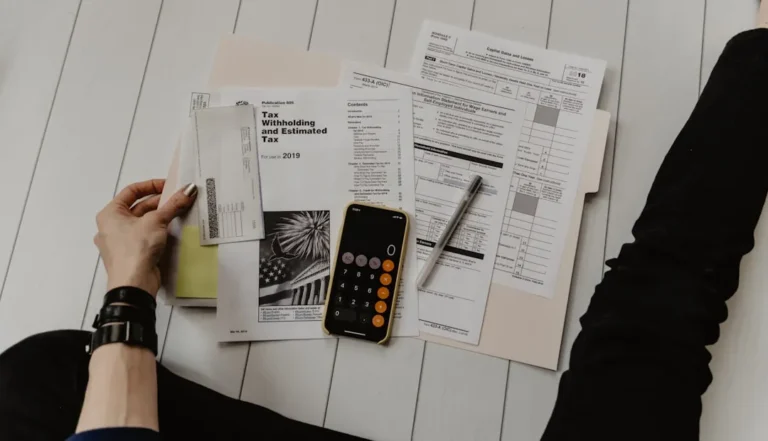 Person Holding Paper Near Pen And Calculator XoU52jUVUXA