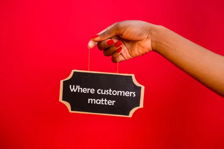 A sign with 'Where customers matter' held by a hand against a vibrant red background.