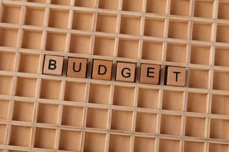 Wooden Scrabble tiles spelling 'budget' on a textured wooden grid, symbolizing financial planning.